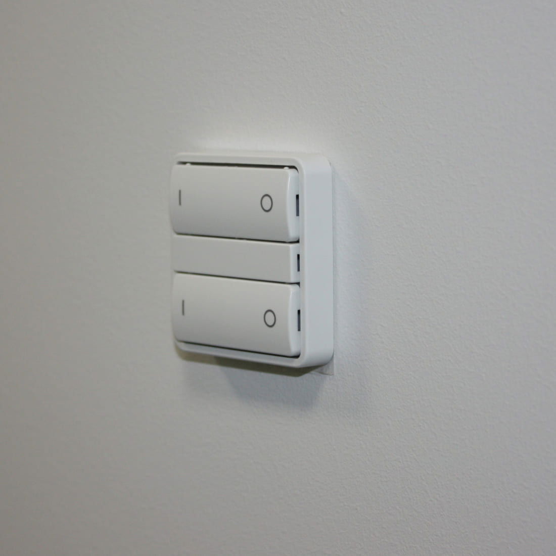 Zigbee Fuga afbryder med svagstrømstangenter, Hue kompatibel i hvid. Afbryderen vist monteret på væg i nærbillede, hvor de fire knapper er tydeligt synlige.