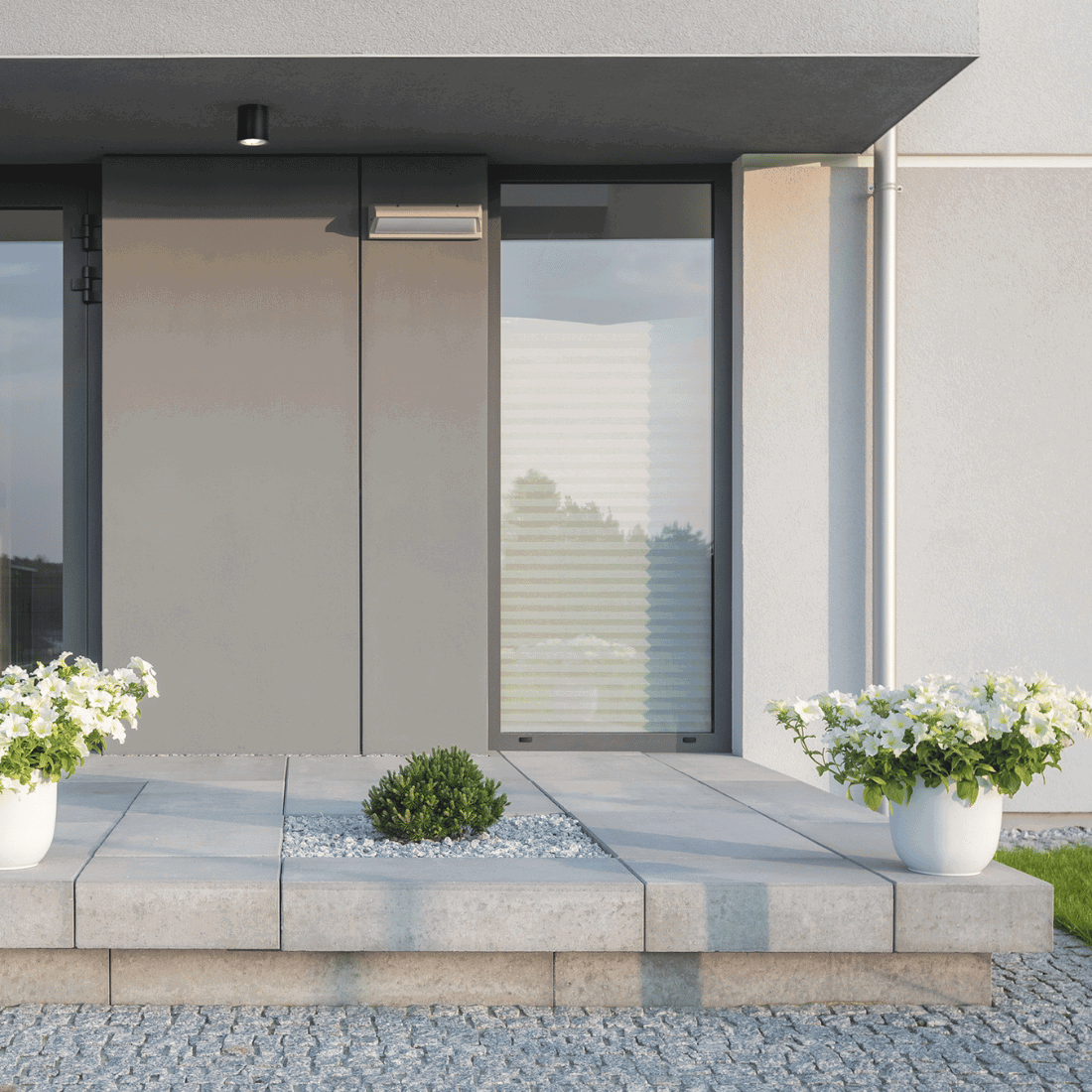 Modern husentré med monterad svart påbyggnadsspot i taket ovanför dörren.