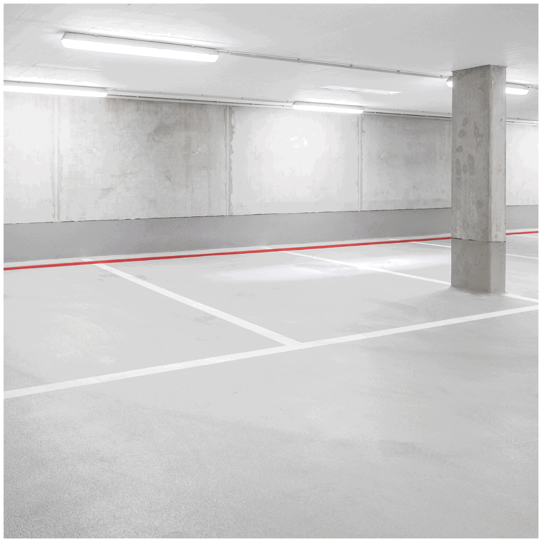 Parkeringskælder oplyst med LED industriarmaturer i loftet, der giver jævn og kraftig belysning.