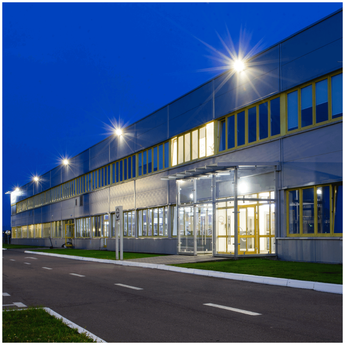 Stor industribygning belyst af LED projektør, hvor stærk udendørsbelysning fremhæver facaden om aftenen.