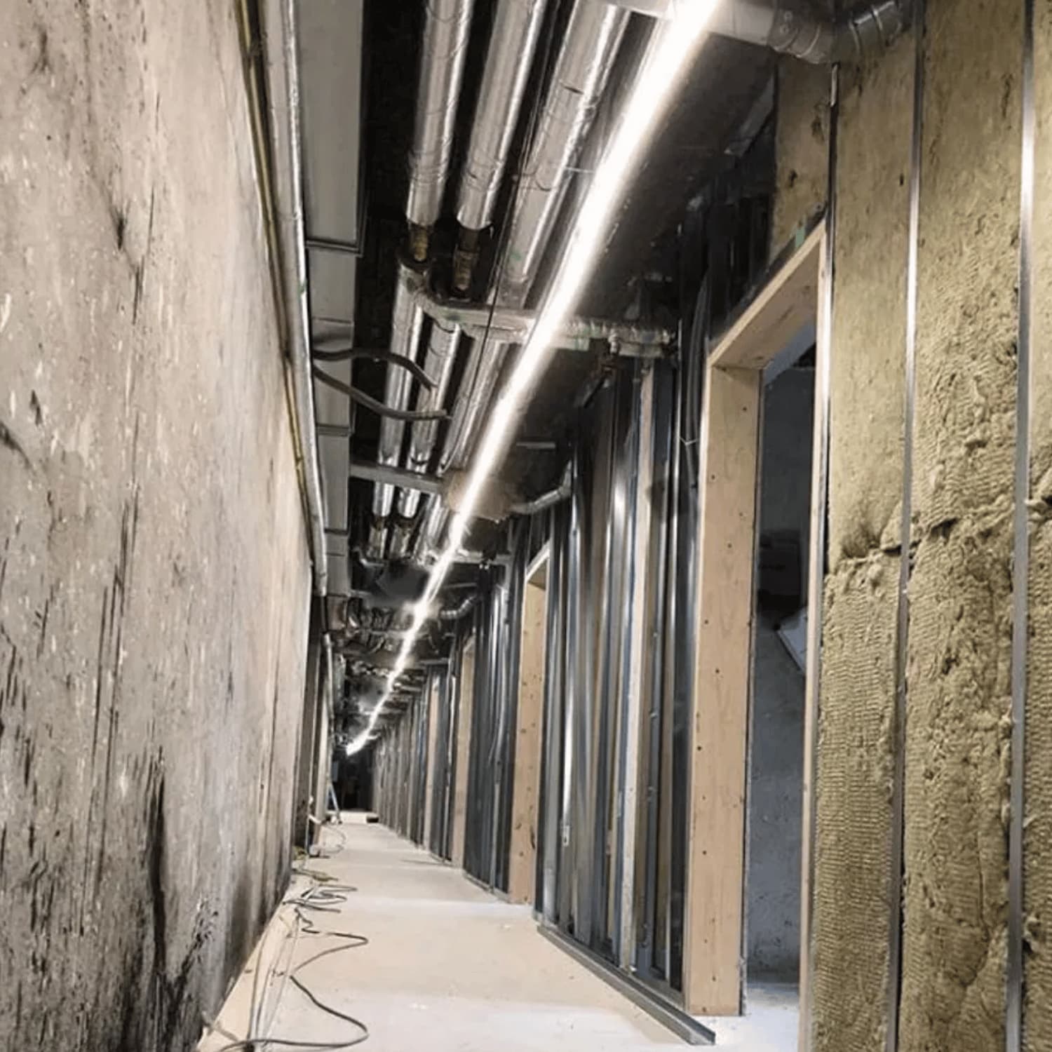 LED-strip trumma 50m, 230V med 1500lm per meter, 4000K neutralvitt och IP65 skyddsklass. LED-bandet är monterat i taket på en rå byggplatskorridor och ger jämn arbetsbelysning.