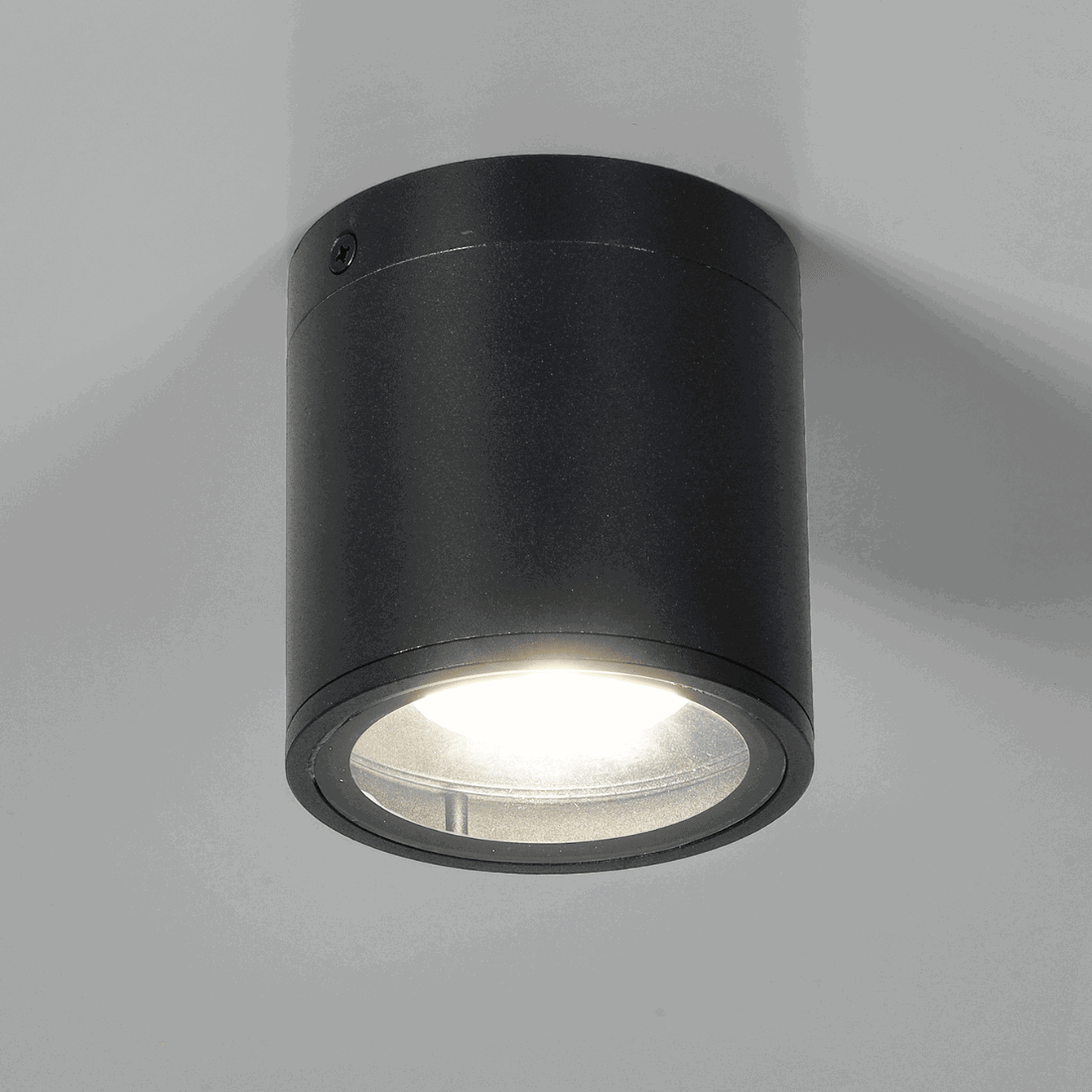 Svart utomhusspot med tänt ljus som lyser nedåt.